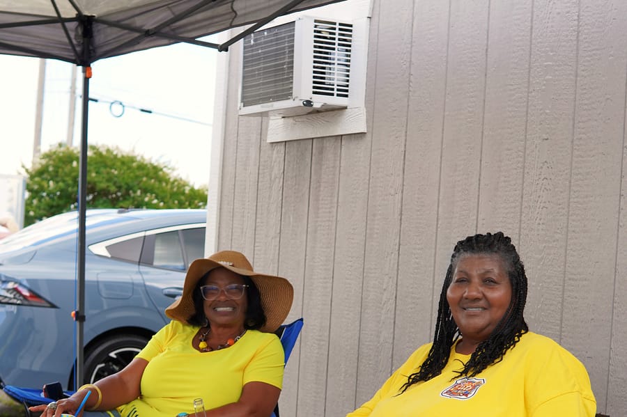 Two Eats on 601 organizers in matching yellow shirts, smiling under the tent